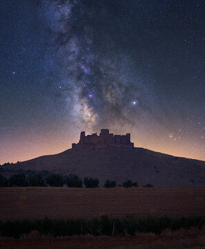 Scenery of field against Almonacid castle on hilltop under shining stars on dark night sky