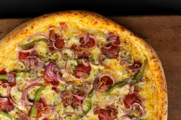 Top view of isolated pizza with cheese, pepperoni or calabresa, red onion, bell pepper, bacon and mushrooms on wooden board 