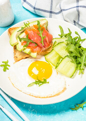 Breakfast. Fried egg, toast with salmon and avocado and fresh salad.