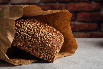 Tasty whole bread with brown crust and sunflower seeds on top on table in daylight