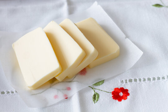 From above slices of butter and aromatic cinnamon sticks for pastry preparation placed on cotton tablecloth on table at home