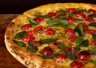 Isolated pizza with cherry tomatoes, basil and mozzarella cheese, or Margherita on wooden board 