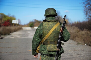 A soldier with a assault rifle and body armor on a blurred background. Automatic weapons.