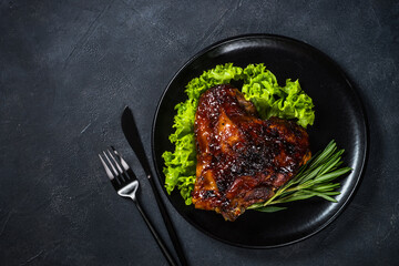 Roast turkey thigh with cranberry sauce and herbs. Top view at black table.