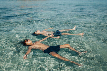 Two boys relaxed on the beach in summer while floating on the sea water