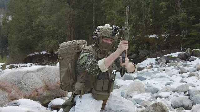 Army Man wearing Tactical Uniform and holding Machine gun in the Outdoor Rain Forest. Winter Warfare. Taken in British Columbia, Canada. Slow Motion. Clip Reload