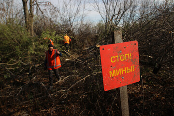 red sign "stop mines" against the background of workers in orange uniform