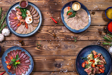 Meat and sausage cuts, garlic, chili peppers, tomatoes and other spices on a wooden brown background.