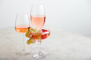 Rose wine in different wine glasses on white table with grapes. Wine composition on light concrete background. modern still life with copy space