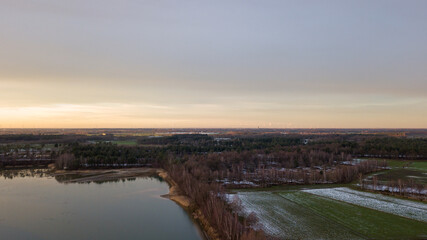 Aerial view of a beautiful and dramatic sunset over a forest lake reflected in the water, landscape drone shot. Blakheide, Beerse, Belgium. High quality photo
