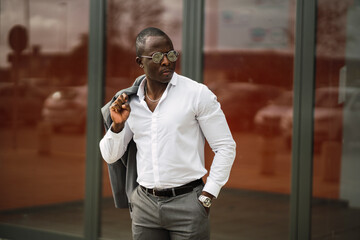 Adult African American male entrepreneur in formal clothes and chain with earring on blurred background in sunlight