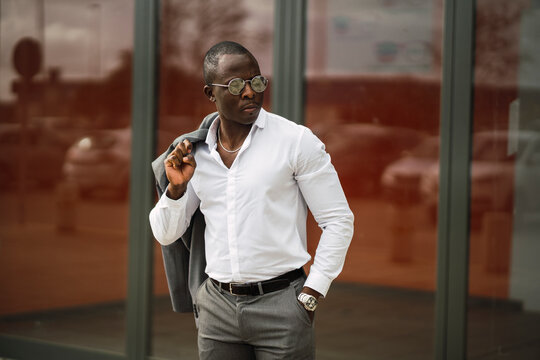 Adult African American male entrepreneur in formal clothes and chain with earring on blurred background in sunlight