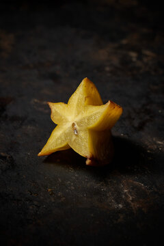 Side view of a carambola cut in half on rustic wooden background