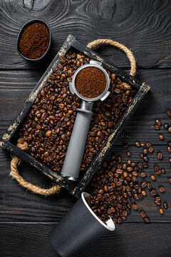 Ground Coffee in Portafilter for Espresso in a wooden tray with coffee beans. Black wooden background. Top view © Vladimir