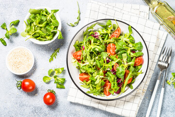 Green salad with arugula, lamb and tomatoes. Healthy vegan dish. Top view at white table.