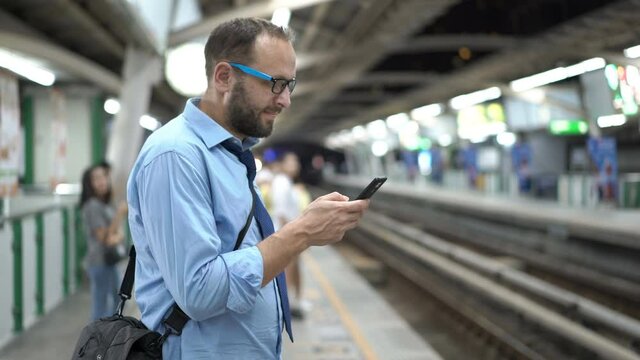 Young businessman texting on smartphone while standing at train station