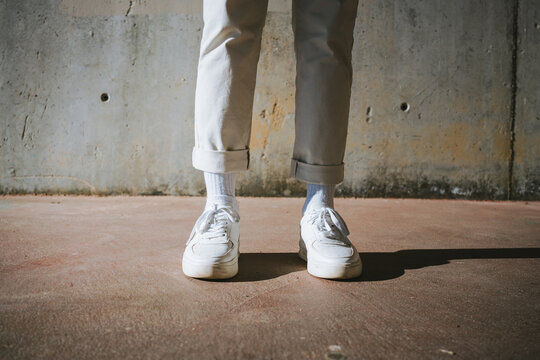 From above of crop unrecognizable trendy guy in stylish sneakers while standing on street on sunny day
