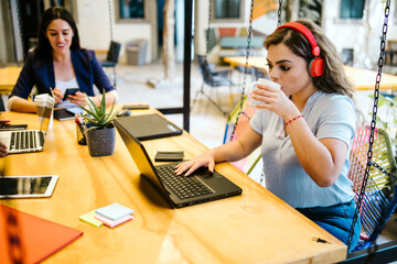 latin woman working with laptop and drinking coffee in a creative office in Mexico city
