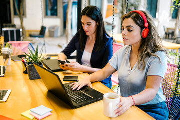 mexican women working with laptop and drinking coffee in a creative office in Mexico city