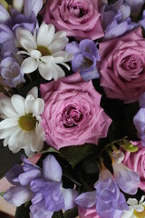 A bouquet of pink roses, white chamomile and blue freesias.