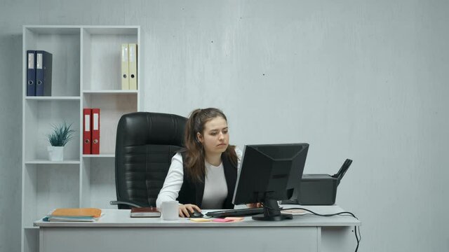 An office employee performs work on a computer. Failure during important work. The girl breaks the printer while working at the computer. The concept of working in the office.