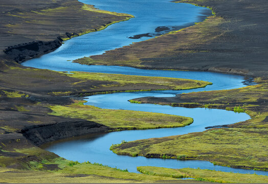 From above of picturesque landscape of bright blue river flowing among volcanic terrain in Iceland