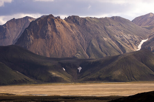 Amazing landscape of rocky dramatic mountain range near green hills and peaceful lake in wild highlands in Iceland