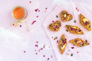 Homemade apple muesli bars, decorated with dried apple and pumpkin seeds, lying on a pale pink...