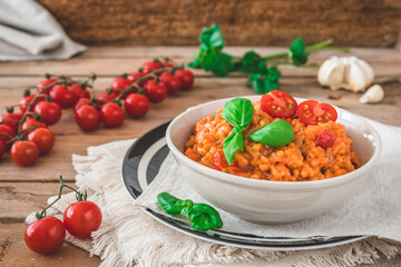 Homemade tomato risotto with fresh basil on a rustic wooden table