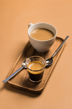 From Above Composition With Cups Of Hot Espresso And Latte Coffee Drinks Served On Wooden Tray With Teaspoons On Beige Background