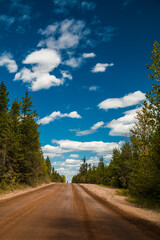 countryside dirt road with blue sky and fluffy white clouds
