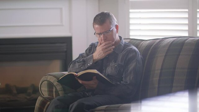 businessman reading bible on sofa