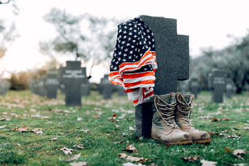 National American flag and army flag placed on gravestone in military cemetery on early autumn day