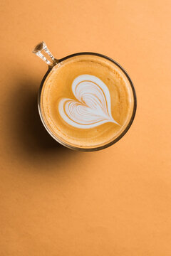 Glass cup of fresh hot aromatic cappuccino with latte art in shape of heart served on table