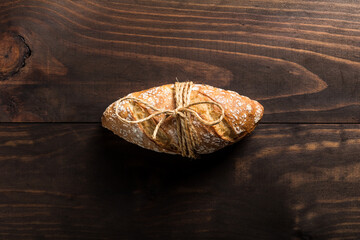Top view of appetizing artisan bread loaf with golden crispy crust placed on wooden table