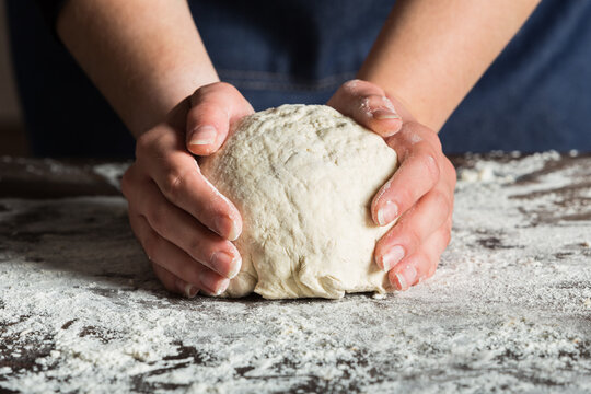 Crop anonymous baker kneading dough on table with flour while preparing bread in bakery