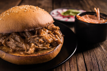 Closeup of yummy hamburger with juicy pulled pork and vegetables in toasted bun