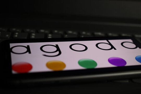 Viersen, Germany - March 1. 2021: Closeup of mobile phone screen with logo lettering of agoda online travel agency on computer keyboard