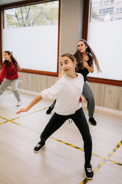 Group of young women and girls rehearsing hip hop dancing movements while practicing in spacious hall together during active lesson with instructor