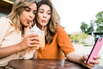 Two friends taking selfie with phone.