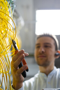 From below blurred male technician with wire cutters working with electronic system of server room