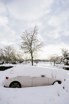 Side view of covered with snow white car in town in sunlight