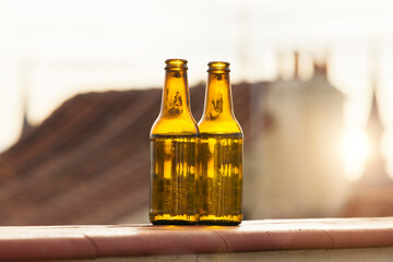 Pair of beer bottles on balcony wall at sunset
