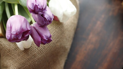 Tulipany na worku jutowym i stole brązowym ciemnym