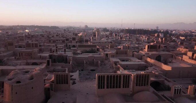 Ruins of Old Adobe House in Ancient Historical Village of Ardakan Old City in Yazd in Iran With Mudbrick Houses and Old air conditioner Badgirs Morning Sunrise Time Mosque and Mountain in Background