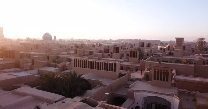 Sunrise and Rotate Aerial View of Old City of Ardakan Yazd in Iran - Adobe Village with Mudbrick Walls and Badgirs Windcatcher Ancient Old Historical Air Conditioner in the Middle of Desert