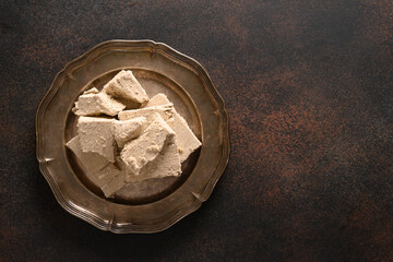 Tasty sweet dessert halva prepared from sunflower seeds on brown background with copy space. View from above.