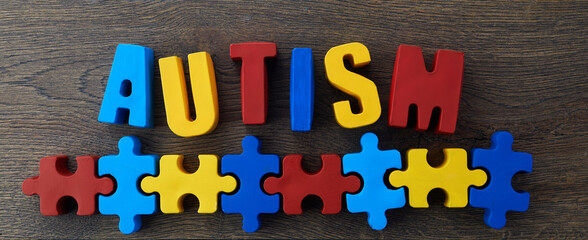 Autism awareness concept with puzzle and word autism on wooden background.