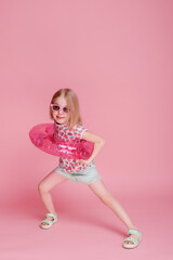 Little girl having fun in an inflatable water circle on a pink background