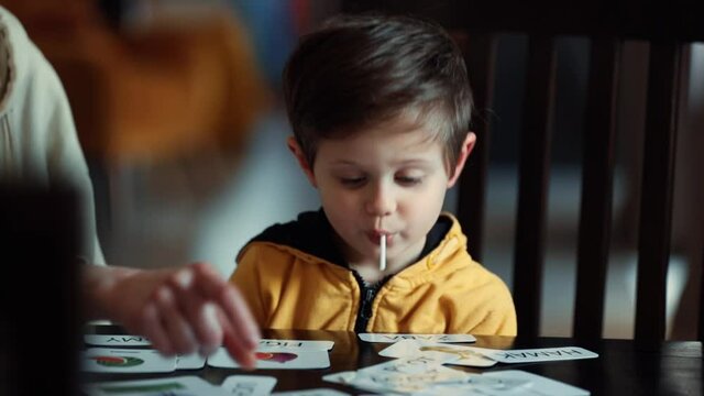 little boy learns words from cards under the ABA therapy program at home at the table